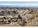 An aerial shot showcases a quaint neighborhood framed by lush trees, with a picturesque backdrop of distant mountains and a golf course at 3145 S Ash St, Denver, CO 80222