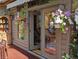 Inviting patio features french doors, beautiful hanging flowers, and a glimpse into a cozy living space at 32209 Blue Springs Dr, Evergreen, CO 80439