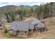 A charming log cabin home nestles among lush greenery with a mountain backdrop at 32209 Blue Springs Dr, Evergreen, CO 80439