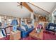 Spacious living room with vaulted ceilings, exposed beams, a blue leather sofa, and hardwood floors at 32209 Blue Springs Dr, Evergreen, CO 80439
