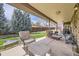 Relax on the large covered patio with chairs and a view of the fenced backyard at 6922 W Walden Pl, Littleton, CO 80128
