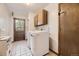 Bright laundry room with front loading washer and dryer, cabinets, tile floor and access to the backyard at 6922 W Walden Pl, Littleton, CO 80128