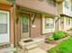 Inviting brick townhome entrance with green trim, a small garden, and a 