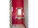 Stylish powder room featuring bold red walls, patterned wallpaper, and a vanity with gold fixtures and a marble countertop at 1641 S Corona St, Denver, CO 80210