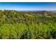 Lush green forest hillside with a view of distant mountains at 13007 Kuehster Rd, Littleton, CO 80127