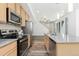 Open kitchen view featuring stainless appliances, wood cabinets, hard surface countertops, and a living area in the background at 5319 Warrior St, Frederick, CO 80504