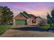 Inviting brick home featuring a green garage door, lush landscaping, and a spacious driveway at 4270 Defoe St, Strasburg, CO 80136