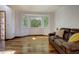Bright living room featuring a bay window, hardwood floors, and a comfortable leather couch at 22739 E Prentice Pl, Aurora, CO 80015