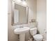 Elegant half bath with pedestal sink, decorative mirror, and neutral color palette at 2559 S Kendrick St, Lakewood, CO 80228