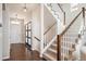 Inviting entryway with a wooden door, decorative lighting, hardwood floors, and staircase with white banisters at 2559 S Kendrick St, Lakewood, CO 80228