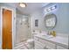 Clean bathroom with a white vanity, white tile shower with glass door, and decorative mirror at 10342 Monterey Cir, Northglenn, CO 80260