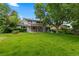 Expansive backyard with a well-maintained lawn, mature trees, and a view of the home's rear facade at 3966 S Magnolia Way, Denver, CO 80237