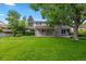 Spacious backyard with lush green grass, mature trees, and a charming two-story home in the background at 3966 S Magnolia Way, Denver, CO 80237
