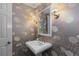 Stylish powder room featuring floral wallpaper, a pedestal sink, decorative mirror, and sconce lighting at 3966 S Magnolia Way, Denver, CO 80237