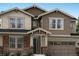 Inviting two-story home featuring stone accents, a covered porch, and a two-car garage at 14571 Hudson St, Thornton, CO 80602