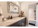 Modern bathroom with a dark vanity, stone countertop, decorative mirror, and a shower/tub at 6211 Stable View St, Castle Pines, CO 80108