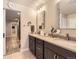 Bathroom with double vanity sinks, decorative mirrors, and view into laundry room at 6211 Stable View St, Castle Pines, CO 80108