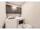 Efficient laundry room featuring front loading washer and dryer and overhead cabinets at 6211 Stable View St, Castle Pines, CO 80108