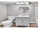 Well-lit bathroom featuring a white vanity, oval mirror, modern lighting, and wood-look flooring at 2074 Oakcrest Cir, Castle Rock, CO 80104