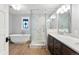 Bright bathroom with a glass-enclosed shower, soaking tub, marble countertops and a vintage-style stained glass window at 4071 S Dahlia St, Cherry Hills Village, CO 80113