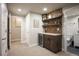 Finished basement wet bar featuring stone backsplash, floating shelves, and a beverage refrigerator at 6780 Canosa St, Denver, CO 80221