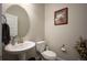 Charming half-bathroom featuring a pedestal sink, round mirror, and elegant decor at 6780 Canosa St, Denver, CO 80221