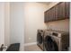 Laundry room with modern washer and dryer, dark cabinets, and a utility sink at 6780 Canosa St, Denver, CO 80221