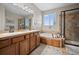 Well-lit bathroom featuring double sinks, soaking tub, and glass-enclosed shower at 42013 Big Horn Cir, Elizabeth, CO 80107
