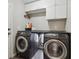 Well-equipped laundry room with washer, dryer, counter space, and overhead cabinets at 8983 W Capri Ave, Littleton, CO 80123