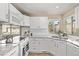 Bright kitchen featuring white cabinets, granite countertops, subway tile backsplash, and stainless steel appliances at 4548 E Kentucky Cir, Denver, CO 80246