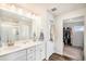 Bright bathroom featuring a double vanity with sleek white cabinetry and a glass-enclosed shower at 12405 E 101St Dr, Commerce City, CO 80022