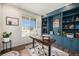 Stylish home office with custom built-ins, modern desk, and a large window showcasing neighborhood views at 12405 E 101St Dr, Commerce City, CO 80022