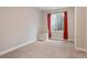 A carpeted bedroom with a window, featuring red curtains at 6735 Avrum Dr, Denver, CO 80221