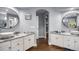 Bright bathroom featuring double sinks with marble countertops, wood floors, and walk-in closet access at 3002 S Oak Way, Lakewood, CO 80227