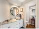 Updated bathroom with modern vanity, marble countertop, vessel sink, and stylish round mirror at 3002 S Oak Way, Lakewood, CO 80227