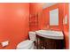 Charming powder room with orange walls and dark wood vanity at 411 S Cody Ct, Lakewood, CO 80226