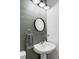 Modern bathroom with pedestal sink, round mirror, and gray shiplap accent wall at 16091 E Geddes Dr # 74, Aurora, CO 80016