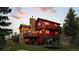 Exterior elevation of a home at dusk showing multi-level decks and a stone chimney at 30717 Conifer Mountain Dr, Conifer, CO 80433