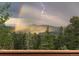 Scenery of mountaintops, trees and sky with rain, a rainbow and lightning at 30717 Conifer Mountain Dr, Conifer, CO 80433