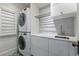 Bright laundry room featuring a stacked washer and dryer, white cabinets, stylish backsplash and unique tile flooring at 553 S Sherman St, Denver, CO 80209