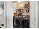 Modern laundry room with side-by-side washer and dryer, and shelving for storage at 8199 Welby Rd # 1903, Denver, CO 80229