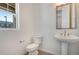 Bathroom features a toilet, sink with pedestal, silver framed mirror and view of the outside at 24563 E 34Th Ave, Aurora, CO 80019