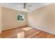 Bright bedroom with hardwood floors, ceiling fan, and a large window overlooking the yard at 1086 Mockingbird St, Brighton, CO 80601