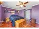Cozy bedroom features wood floors, ceiling fan, bed and a door leading to an ensuite bathroom at 1086 Mockingbird St, Brighton, CO 80601