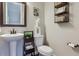 Powder room with a round pedestal sink, toilet, mirror, and decorative shelving at 3698 Penang Dr, Castle Rock, CO 80109