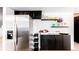 Kitchen with dark cabinets, stainless steel refrigerator, floating shelves, and white walls at 8736 E Easter Ave, Centennial, CO 80112