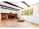 Cozy living room with a brick fireplace, wood floors, beamed ceilings, and a large window at 8736 E Easter Ave, Centennial, CO 80112