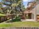 Well-maintained backyard with lawn, trees, wooden deck, and brick wall at 6449 S Jamaica Cir, Englewood, CO 80111