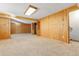View of spacious basement with knotty pine paneling, carpet, and ample room for storage and entertainment at 22815 E Progress Ave, Aurora, CO 80015