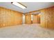 Large basement featuring knotty pine paneling, carpeted floor, and versatile space for recreation and storage at 22815 E Progress Ave, Aurora, CO 80015